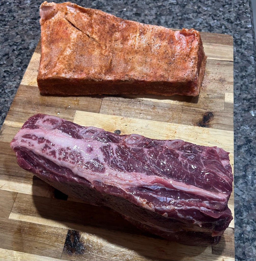 Marbled raw beef cuts on a striped wooden cutting board.
